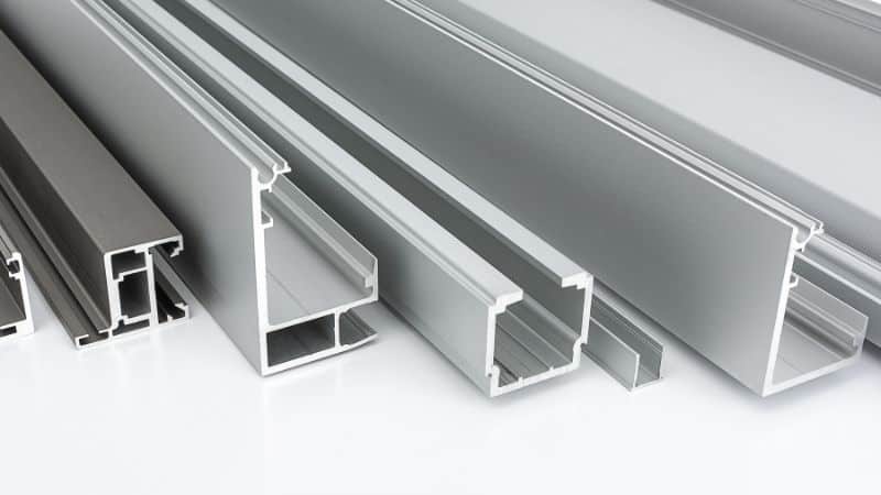 Close-up of various aluminum extrusions on a white surface.