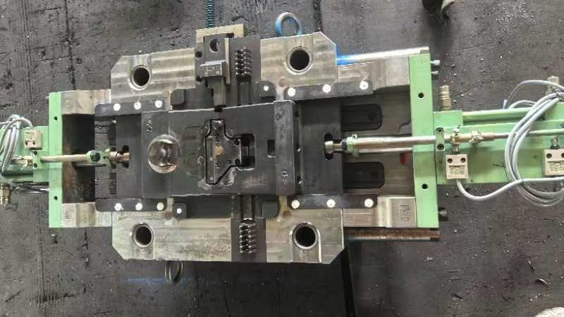 An injection mold with alignment pins, a cavity, and ejector mechanisms on a workshop table.