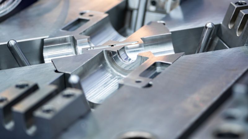 Primer plano de una pieza metálica mecanizada en un molde o accesorio industrial complejo.