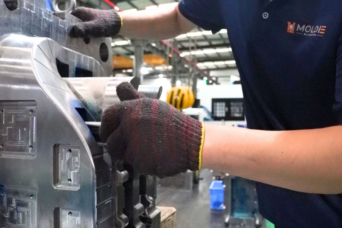 Worker in gloves operating metal casting machinery in a manufacturing plant, showcasing precision and craftsmanship in metal casting.