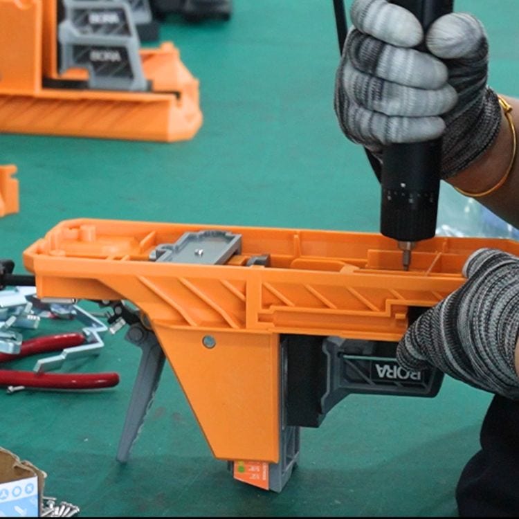 Technician assembling a mold with a power drill in a manufacturing workshop, showcasing industrial equipment and tools.